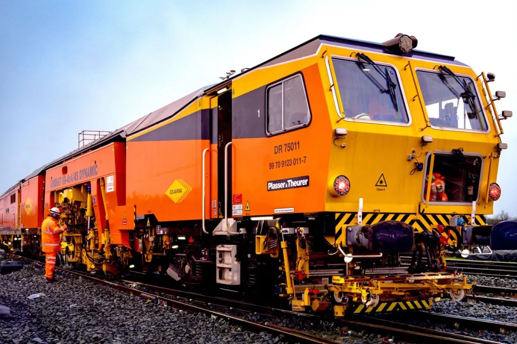 Engin ferroviaire en opération sur voie, collaborateurs en intervention.