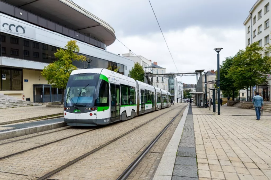  White and green tram that parks at a station