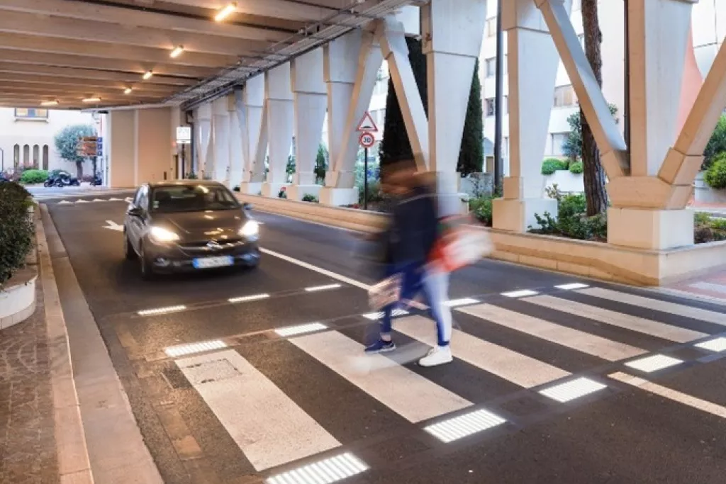 Personne qui marche une un passage piéton lumineux et un voiture qui attends